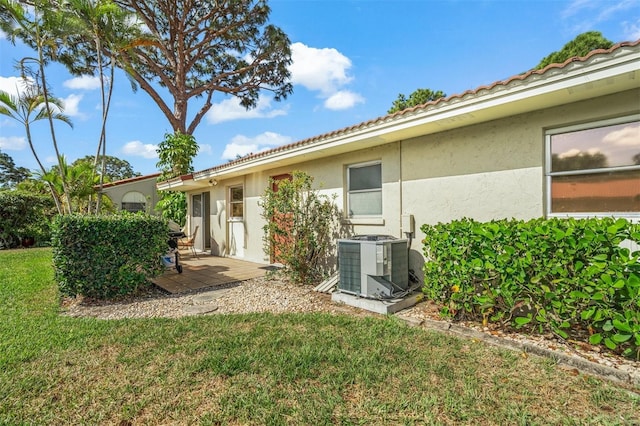 back of property featuring a yard and central AC