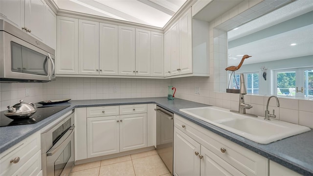 kitchen with white cabinetry, sink, light tile patterned floors, and stainless steel appliances