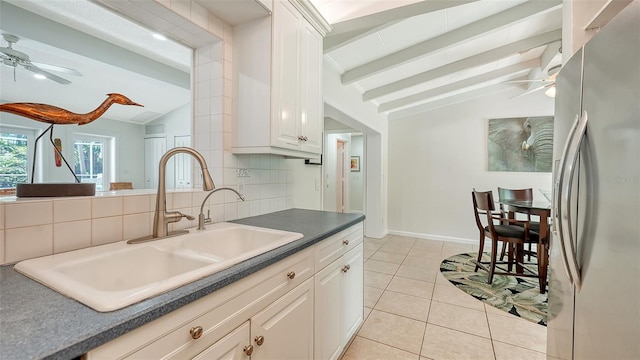 kitchen with backsplash, lofted ceiling with beams, sink, white cabinetry, and stainless steel refrigerator