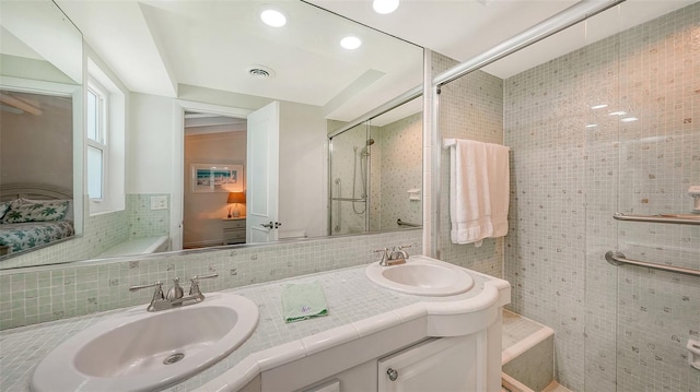 bathroom featuring walk in shower, vanity, and tile walls