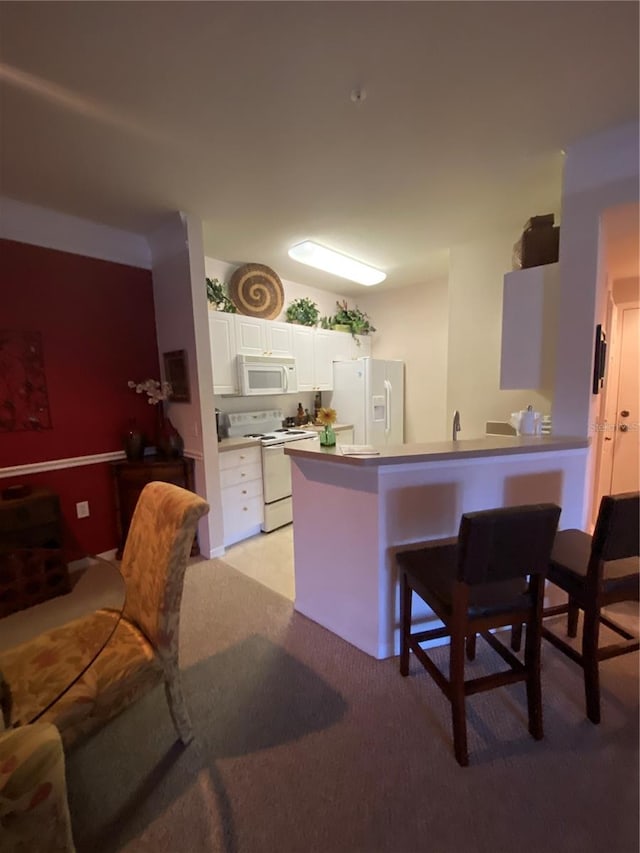 kitchen with kitchen peninsula, white cabinets, white appliances, and light colored carpet