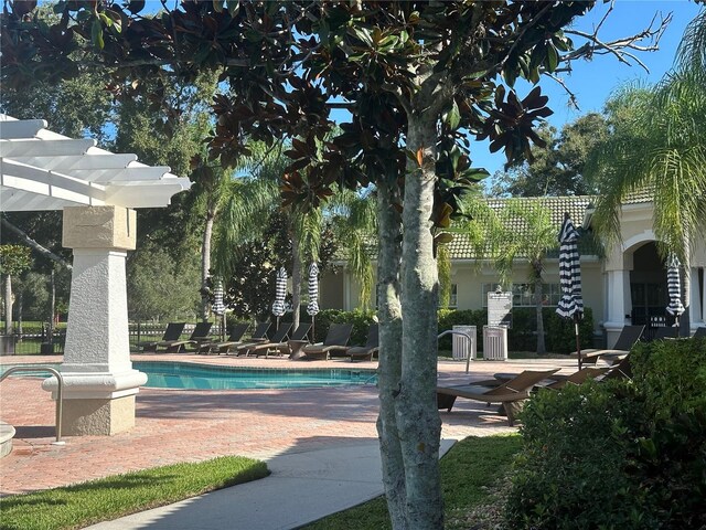 view of property's community with a pool, a patio area, and a pergola