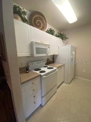 kitchen featuring light tile patterned floors, white cabinets, and white appliances