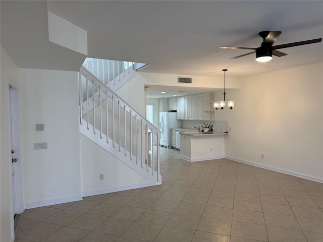 interior space featuring light tile patterned floors and ceiling fan with notable chandelier