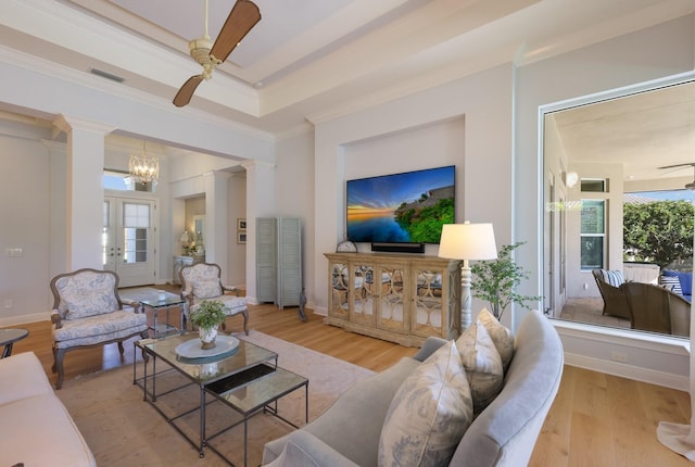 living room featuring ornate columns, french doors, crown molding, ceiling fan with notable chandelier, and light wood-type flooring