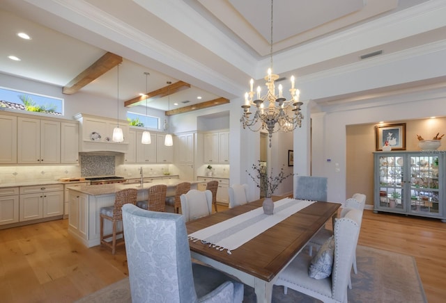 dining space featuring a notable chandelier, light hardwood / wood-style floors, sink, and a tray ceiling