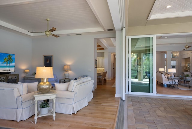 living room with ceiling fan, beamed ceiling, and light hardwood / wood-style floors