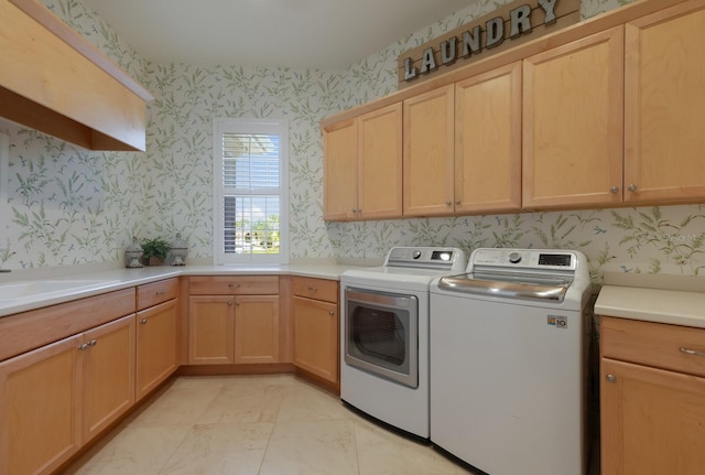 clothes washing area with cabinets, washing machine and dryer, light tile patterned flooring, and sink