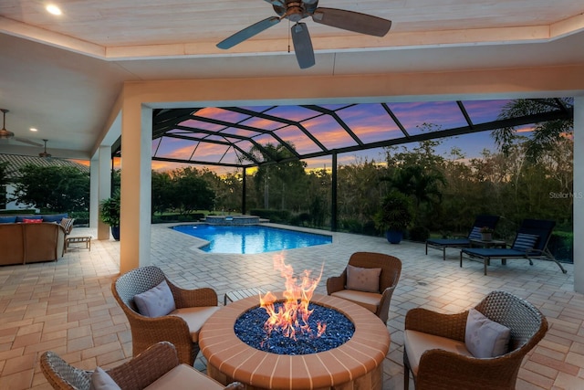 pool at dusk featuring a patio, glass enclosure, and ceiling fan