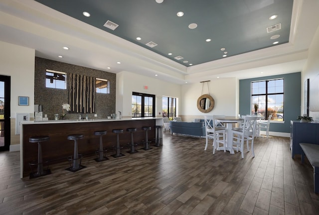 kitchen with dark hardwood / wood-style floors, a kitchen breakfast bar, kitchen peninsula, and a tray ceiling