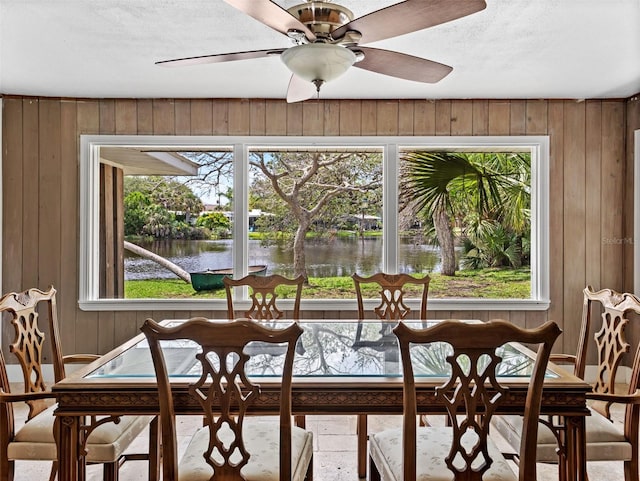 sunroom featuring ceiling fan, a water view, and plenty of natural light