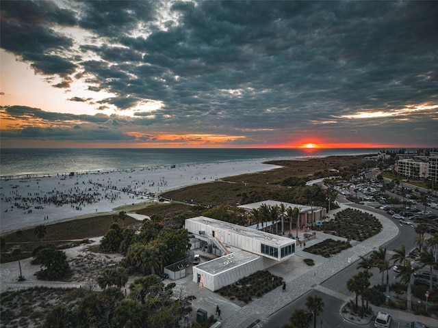 aerial view at dusk with a water view and a beach view