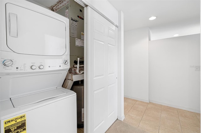 laundry room with light tile patterned floors and stacked washer / dryer