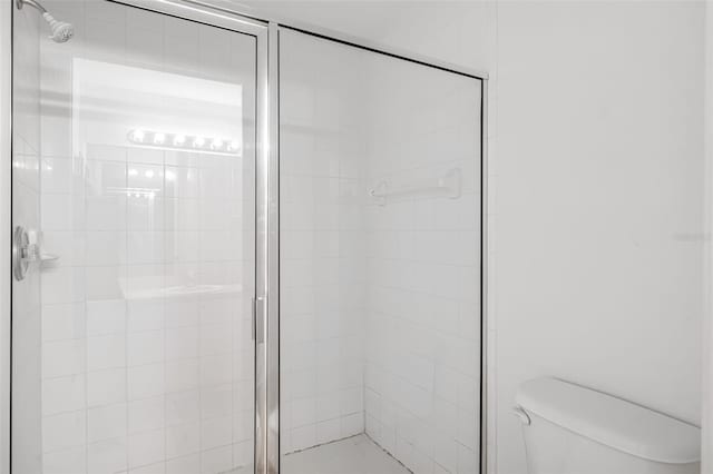 bathroom featuring toilet and a shower with shower door