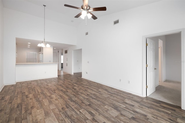 unfurnished living room with dark hardwood / wood-style flooring, high vaulted ceiling, and ceiling fan with notable chandelier