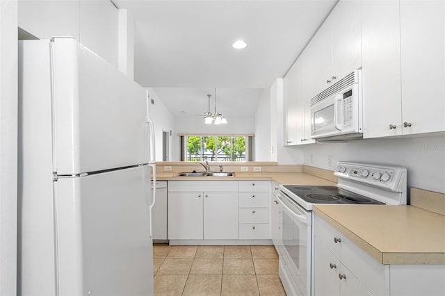 kitchen featuring white appliances, sink, pendant lighting, white cabinets, and a chandelier