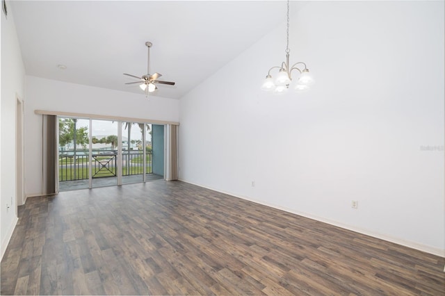 unfurnished room featuring a towering ceiling, ceiling fan with notable chandelier, and dark wood-type flooring