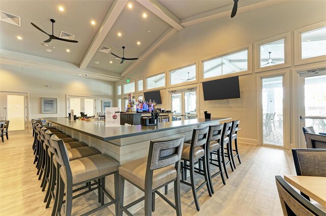 kitchen featuring a kitchen breakfast bar, ceiling fan, beam ceiling, high vaulted ceiling, and light hardwood / wood-style floors