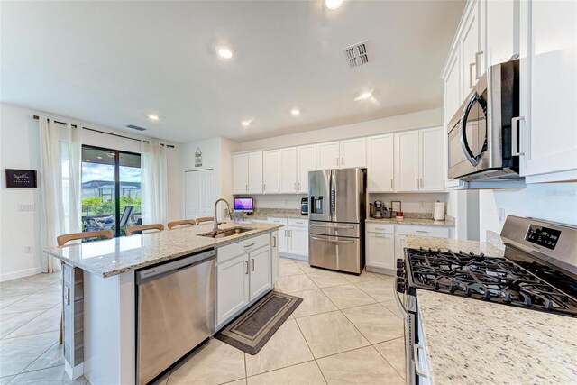 kitchen with a breakfast bar, light stone countertops, white cabinetry, and stainless steel appliances