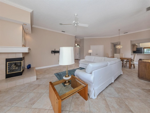 living room featuring a tiled fireplace, ceiling fan, a textured ceiling, and ornamental molding