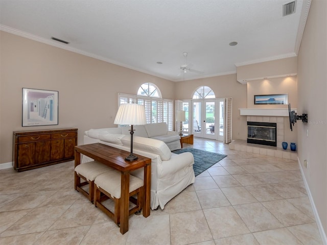 tiled living room featuring ceiling fan, ornamental molding, and a tiled fireplace