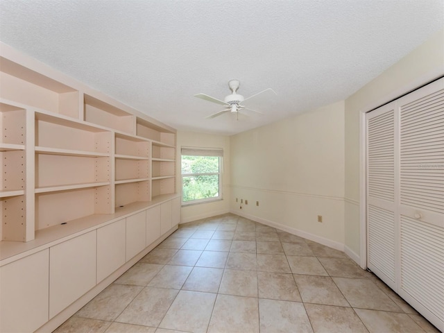 interior space featuring ceiling fan, built in features, and a textured ceiling