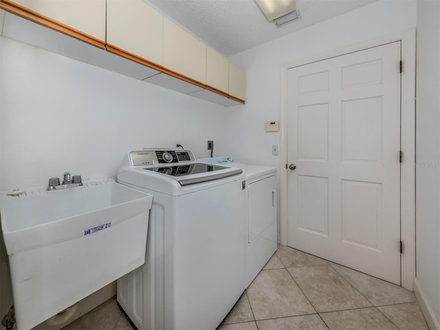 laundry area featuring sink, cabinets, separate washer and dryer, a textured ceiling, and light tile patterned floors