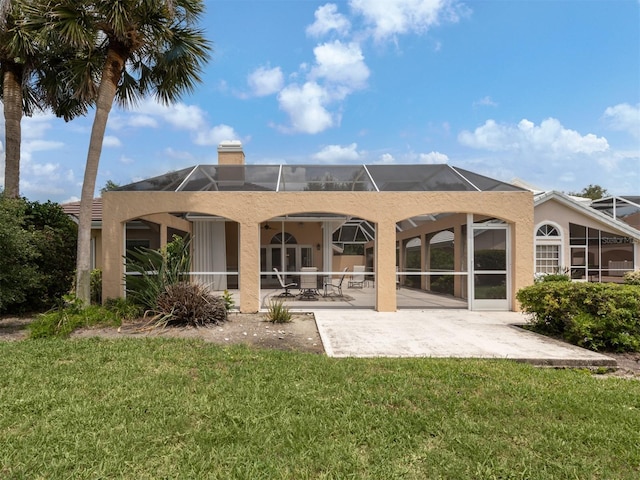 back of property featuring glass enclosure, a patio area, and a lawn