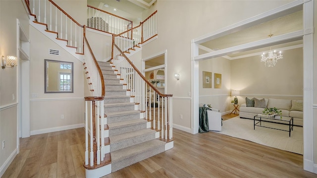 staircase featuring hardwood / wood-style floors, a chandelier, and a towering ceiling