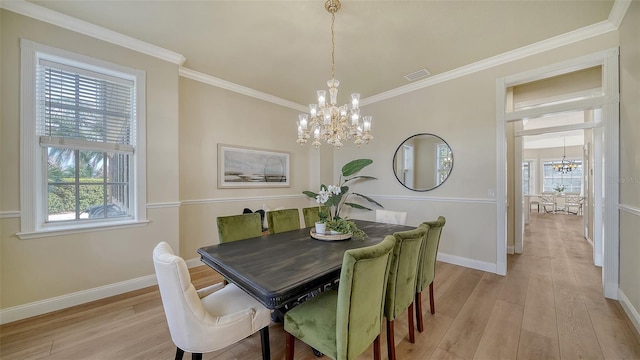 dining area with light wood-type flooring, an inviting chandelier, crown molding, and a wealth of natural light