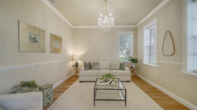 living room with crown molding, a chandelier, and light hardwood / wood-style floors