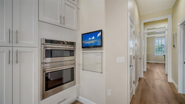 kitchen featuring white cabinetry, hardwood / wood-style floors, and stainless steel double oven