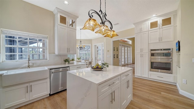 kitchen with appliances with stainless steel finishes, decorative light fixtures, white cabinetry, and a kitchen island