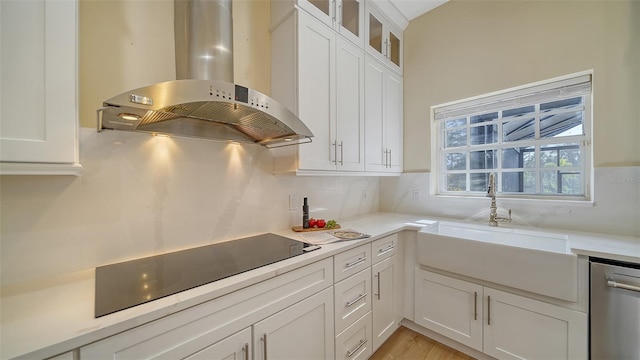 kitchen with sink, island range hood, white cabinetry, stainless steel dishwasher, and black electric cooktop