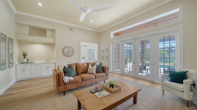 living room with french doors, light hardwood / wood-style flooring, ornamental molding, ceiling fan, and wet bar