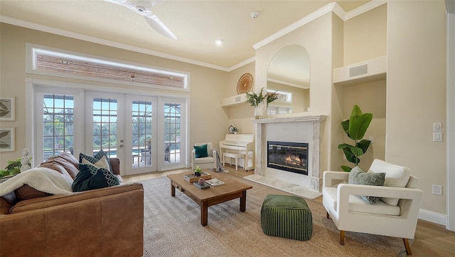 living room featuring hardwood / wood-style flooring, crown molding, french doors, and a high end fireplace