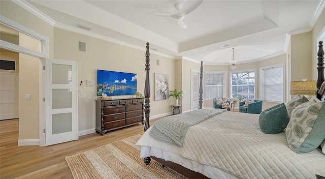 bedroom with a raised ceiling, light hardwood / wood-style flooring, ceiling fan with notable chandelier, and ornamental molding