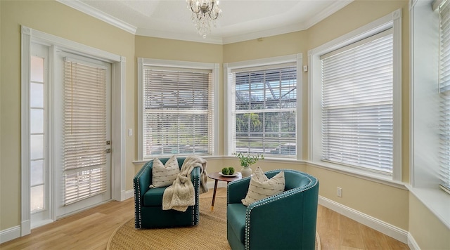 living area featuring hardwood / wood-style flooring, ornamental molding, and a chandelier