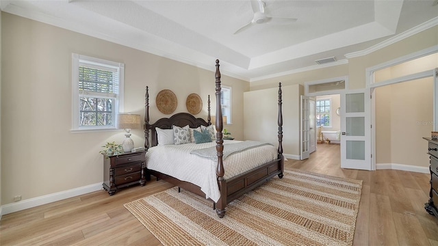 bedroom featuring a raised ceiling, light hardwood / wood-style floors, ceiling fan, and ornamental molding