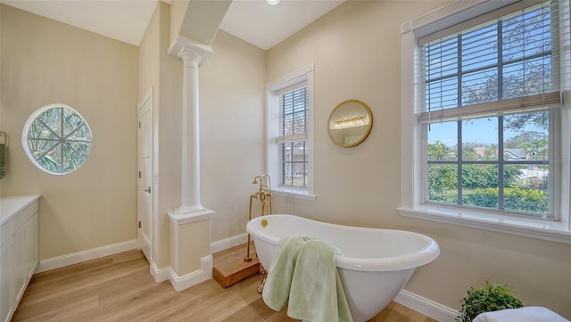 bathroom with hardwood / wood-style flooring, decorative columns, and a bathtub