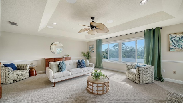 carpeted living room with ceiling fan, a tray ceiling, and a textured ceiling