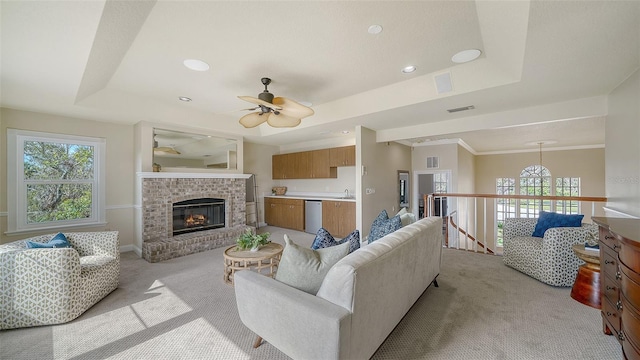 carpeted living room featuring sink, a brick fireplace, a wealth of natural light, and a raised ceiling