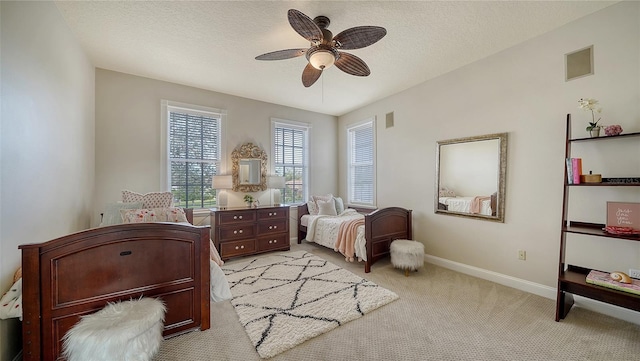 bedroom featuring a textured ceiling, light colored carpet, and ceiling fan