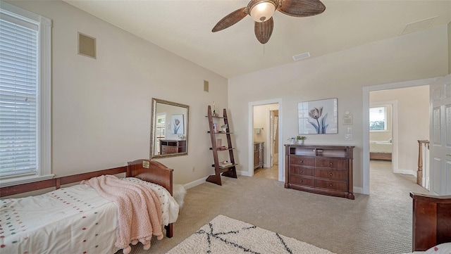 carpeted bedroom with multiple windows, ceiling fan, and ensuite bath