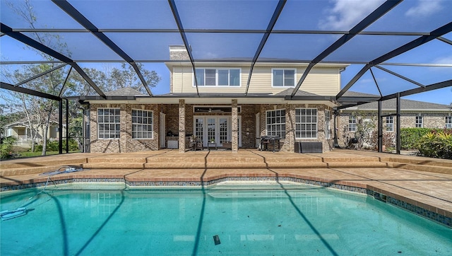 view of swimming pool featuring glass enclosure, a patio area, and french doors