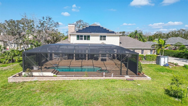 back of house with glass enclosure, a lawn, and solar panels