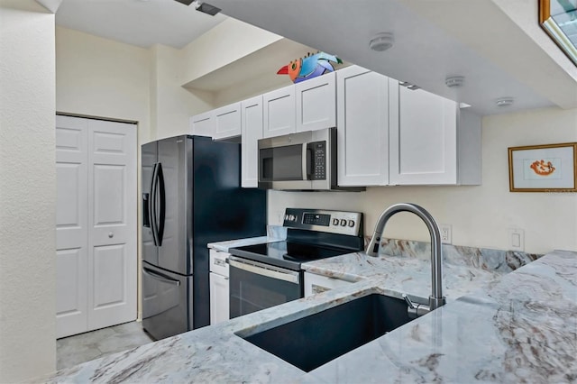 kitchen with light stone countertops, sink, white cabinets, and stainless steel appliances