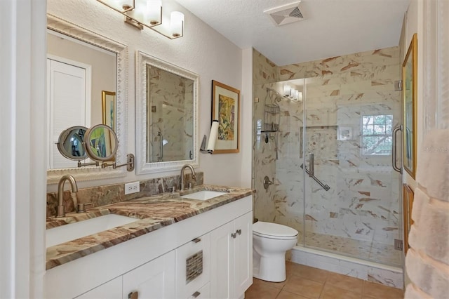 bathroom with vanity, a textured ceiling, a shower with door, tile patterned flooring, and toilet