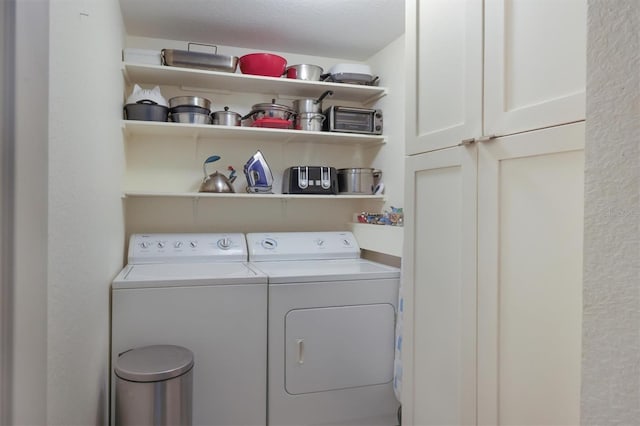 laundry area with cabinets, a textured ceiling, and washing machine and clothes dryer