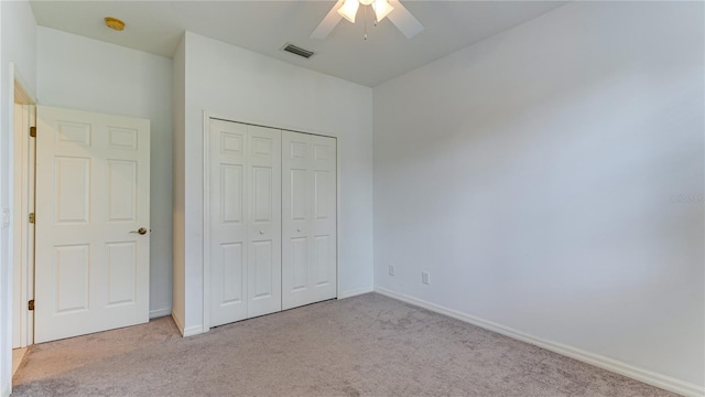 unfurnished bedroom featuring ceiling fan, light colored carpet, and a closet